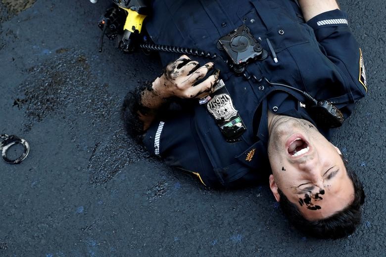 An officer from the New York Police Department is seen injured after attempting to detain a protester smearing paint on the Black Lives Matter mural outside of Trump Tower on Fifth Avenue in Manhattan. REUTERS/Andrew Kelly  
